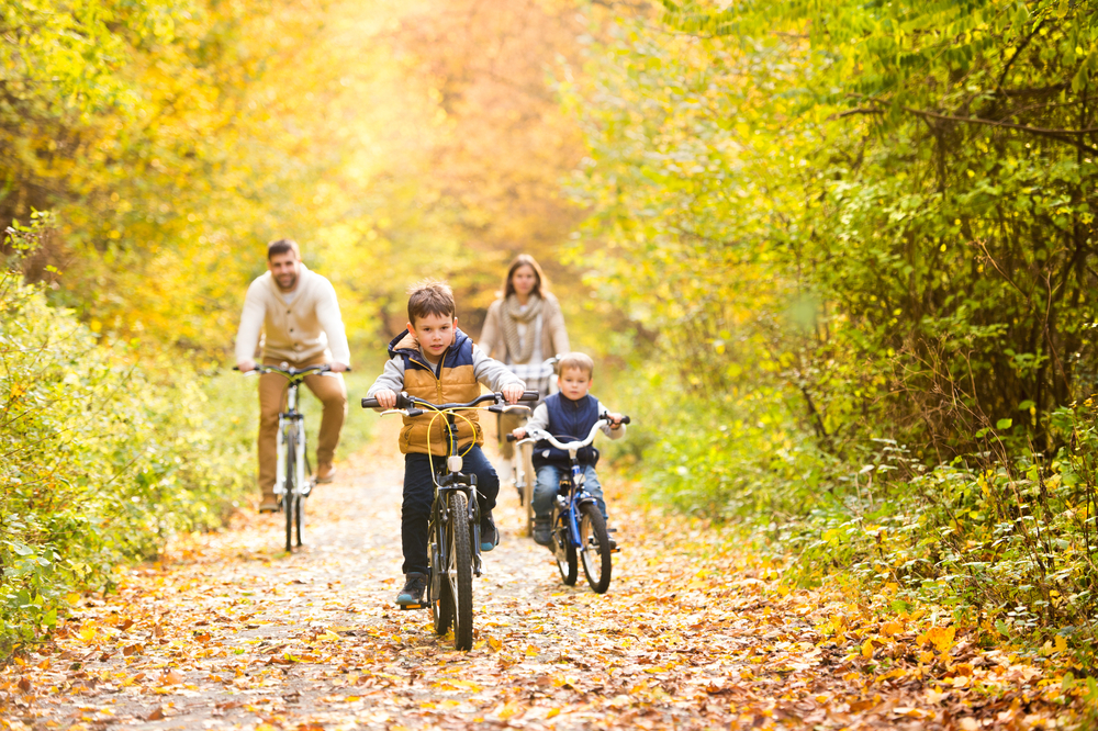 Family cycling down autumnal pathway